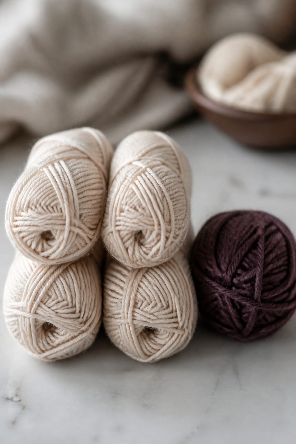A plied worsted-weight skein beside a striped knitted tube topped with a pompom